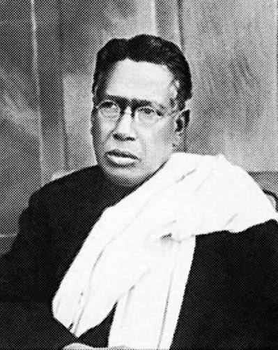 Seated half-length photographic portrait of Bipin Chandra Pal in round spectacles, wearing a dark garment with a white shawl draped over one shoulder.